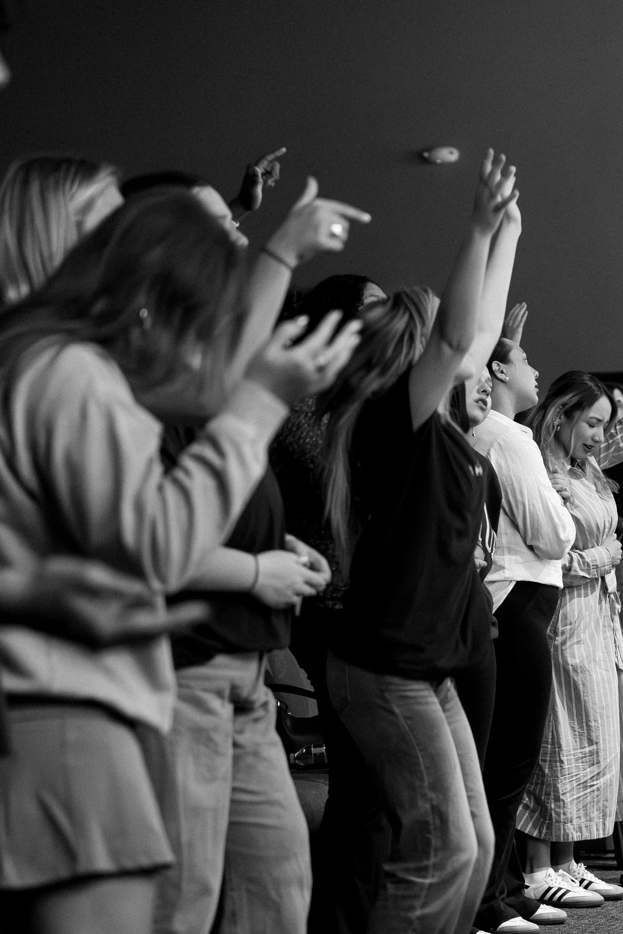 Young adults worshipping together with hands lifted