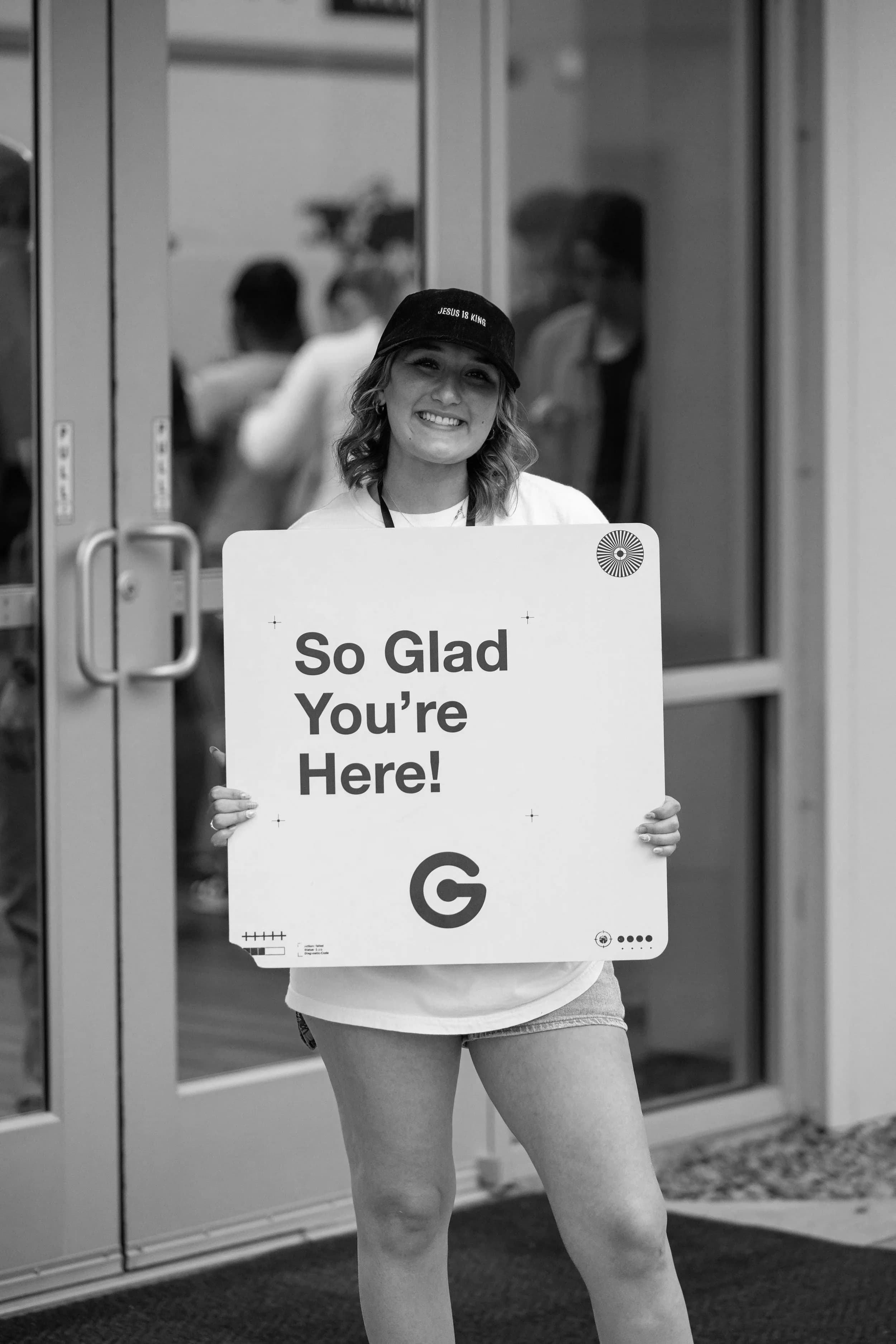 A volunteer holding a “So glad you’re here” sign