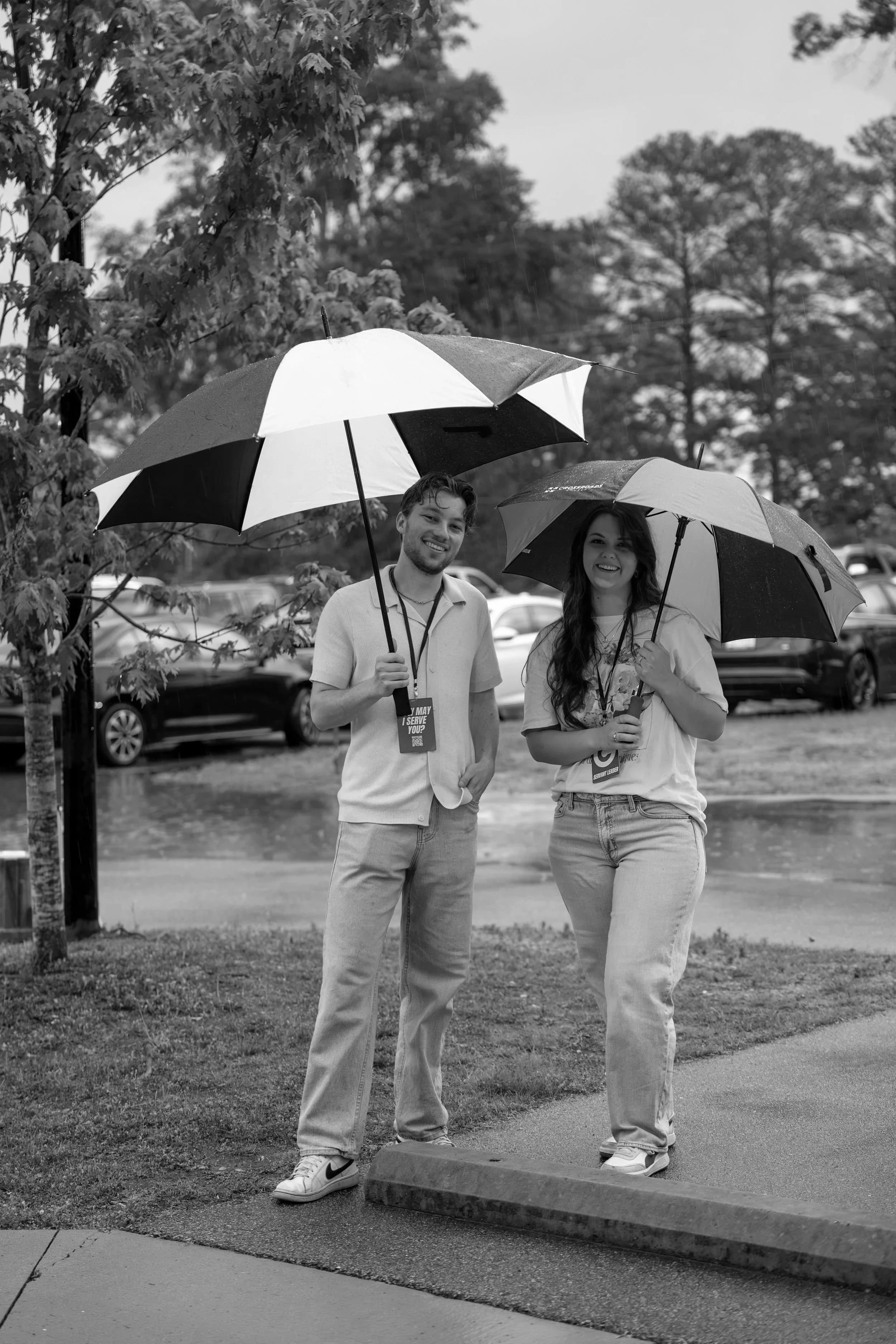 Two volunteers walking guests in under umbrellas