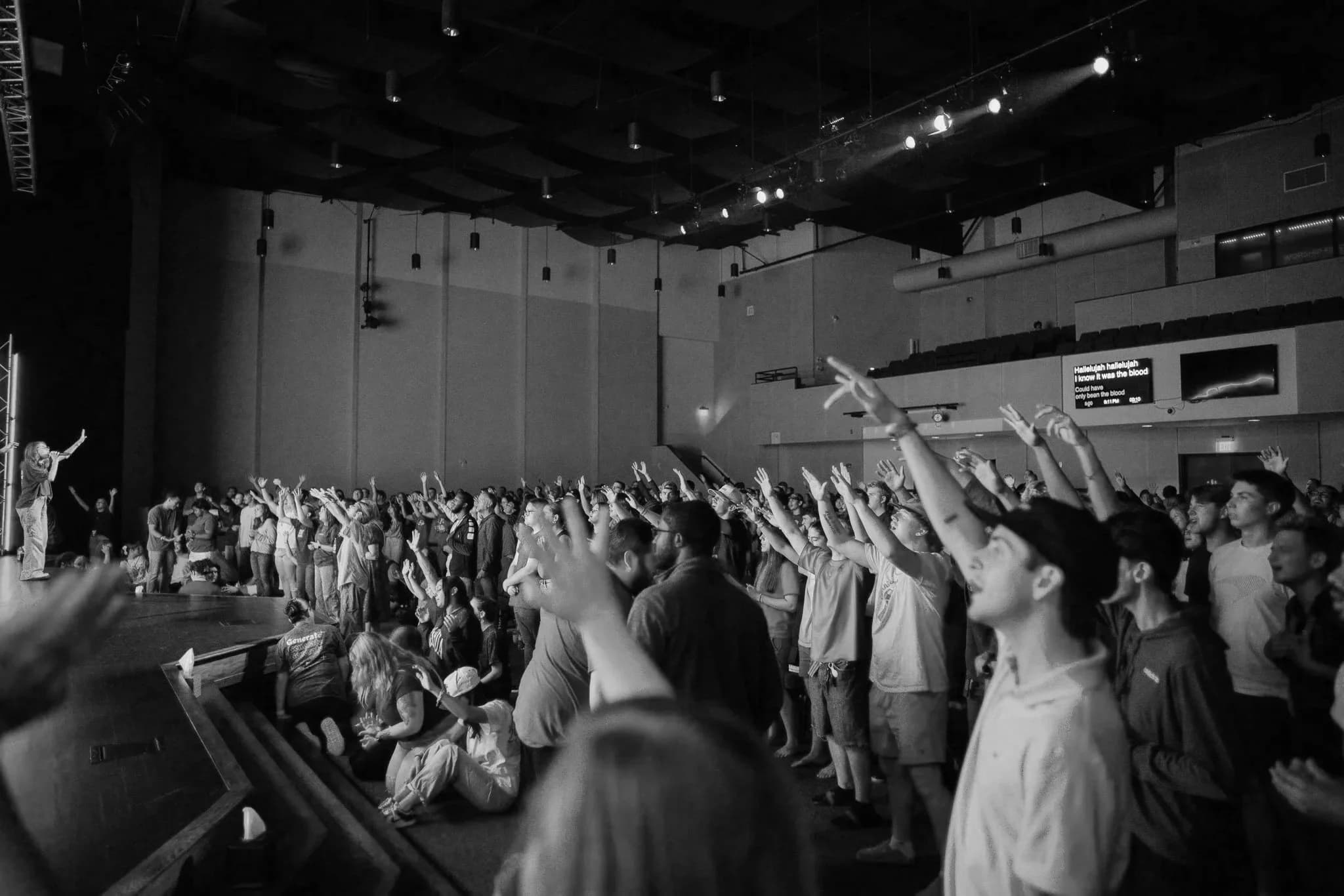 A full room worshipping with hands raised